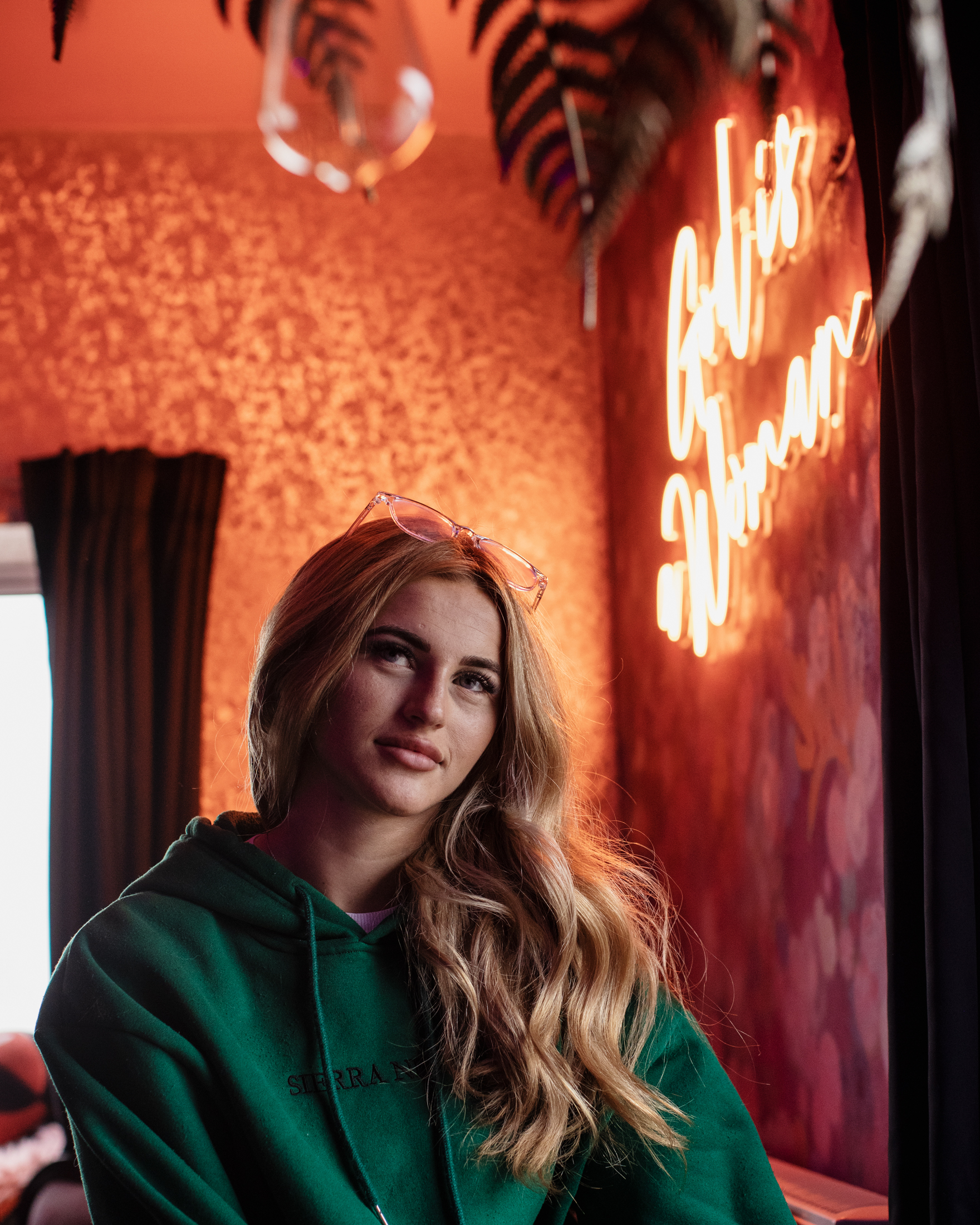 Sophie Aspin looks away from the camera in a warmly lit room with ornate wallpaper.