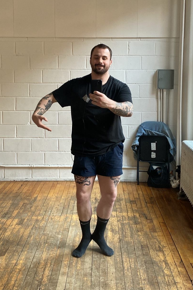A man in socks doing a ballet pose and taking a selfie