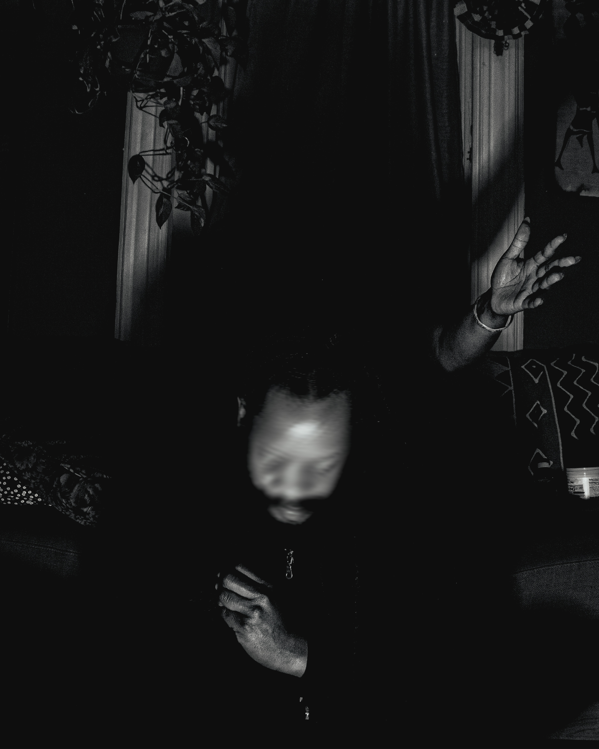 billy woods' moving his face in a blur while a hand comes out of the darkness int he background.