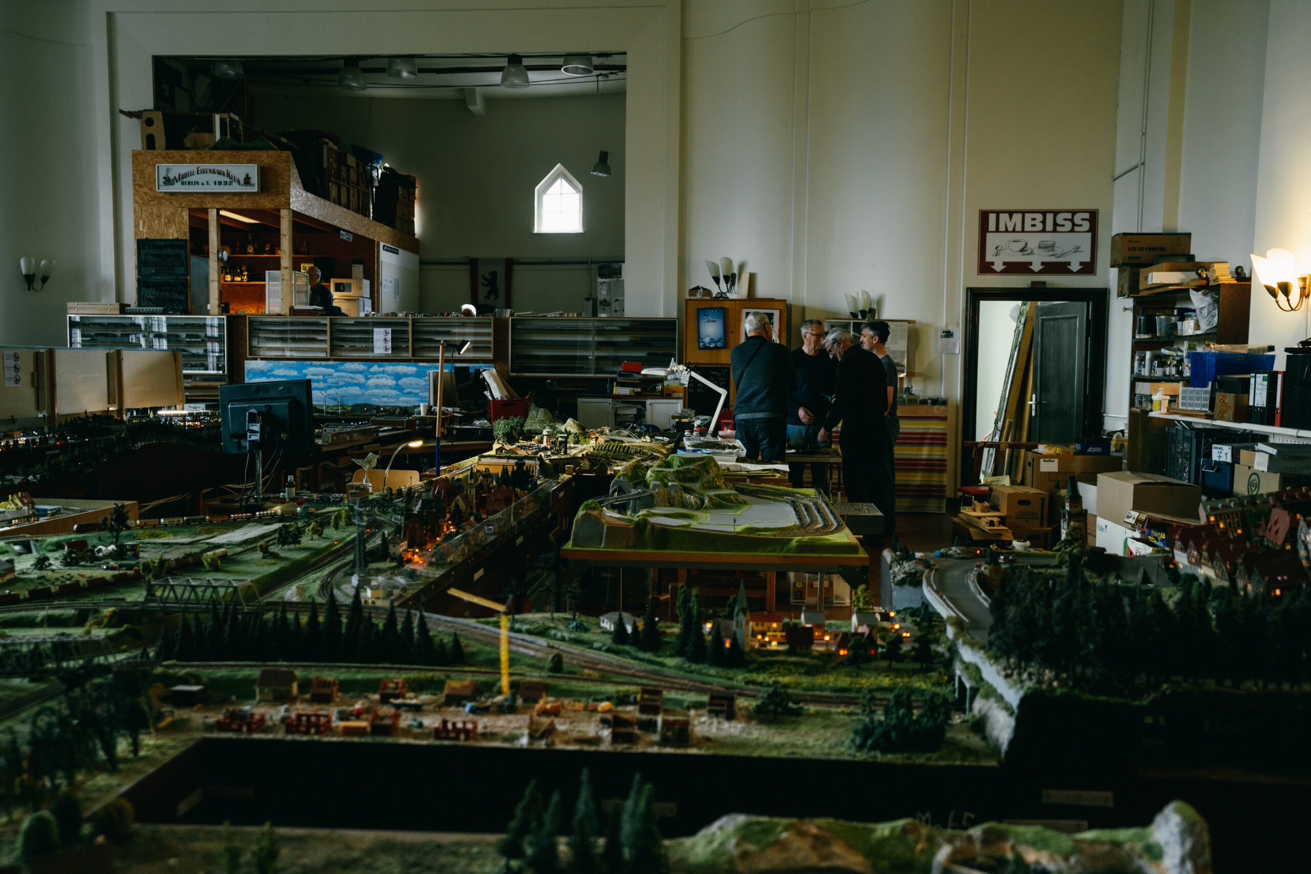 Ein Teil der Modelleisenbahn und vier ältere Männer, die sich unterhalten