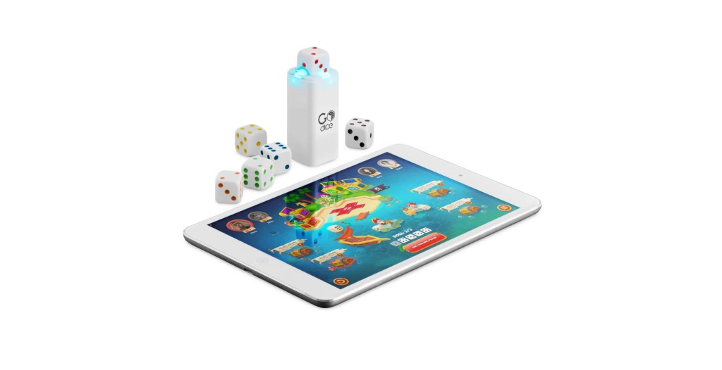 The GoDice by Particula, next to a tablet inside of the charging container